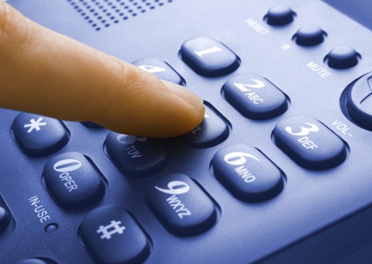 A hand pressing a button on a fax machine.