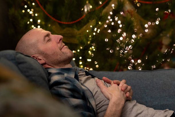 Phiona Hutton Counsellor and Integrative therapist, in person Havant, Hampshire or online nationwide. A man relaxed on a sofa, eyes closed, with festive lights in the background.