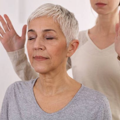 Usui Shiki Ryoho Reiki Training A calm, elderly woman with short grey hair, eyes closed, meditating with a person behind her.