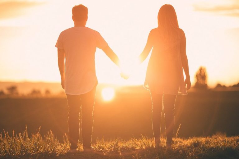 Couples and relationship couselling Silhouetted couple holding hands against a sunset backdrop.