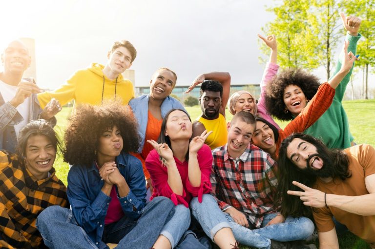 A diverse group of people smiling and posing cheerfully outdoors.